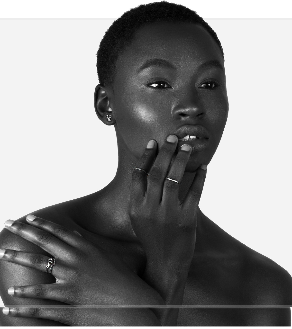 Black and white portrait of a woman with gold jewelry on a white background, featuring the brand 'HerOnlyNecessity'.